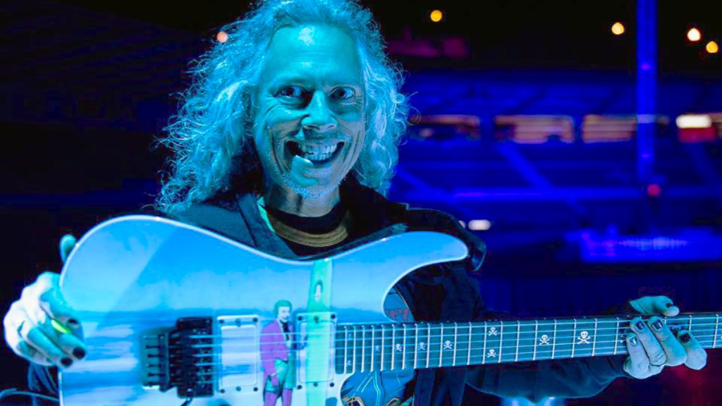 Kirk Hammett from Metallica holding a guitar with DC's Joker on it