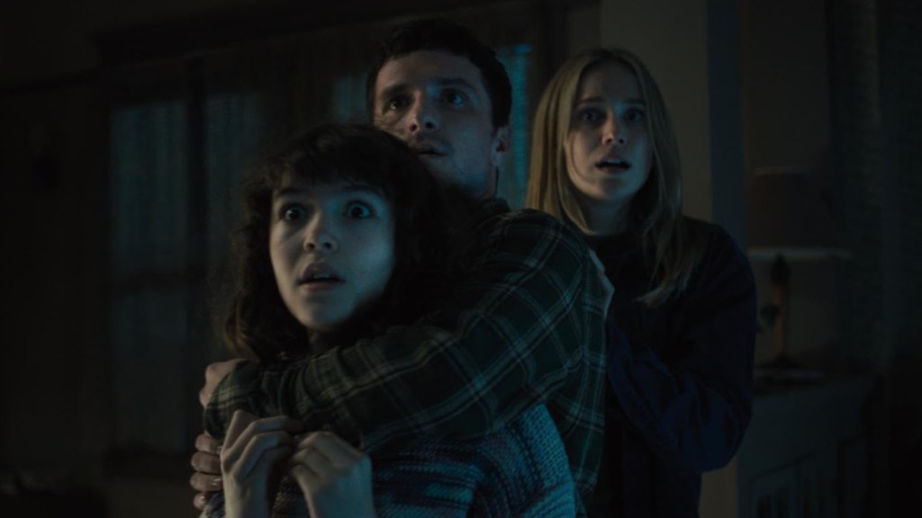 A man holds a young girl with a woman behind them.