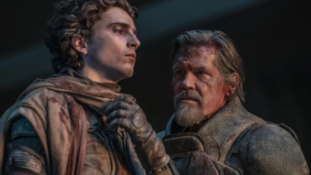 A man stares at another man looking into the distance.