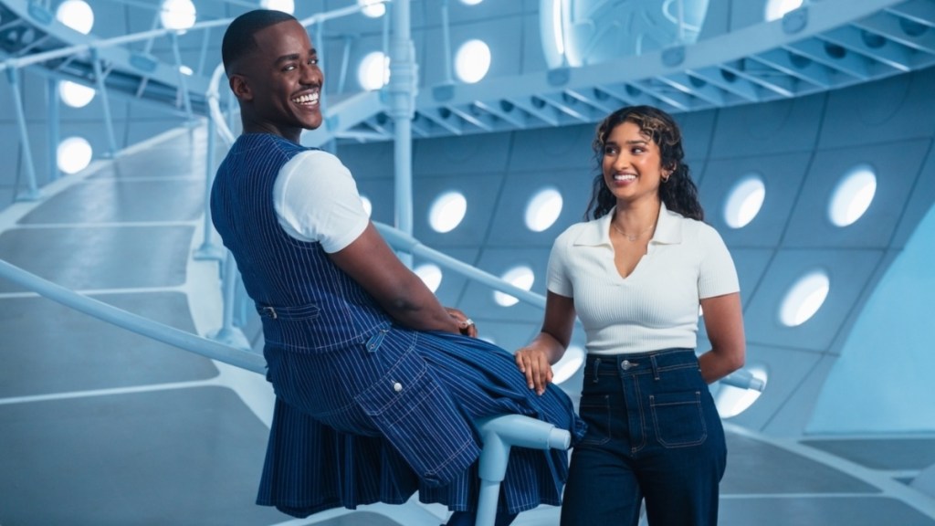 A man sits over a rail as a girl looks at him.