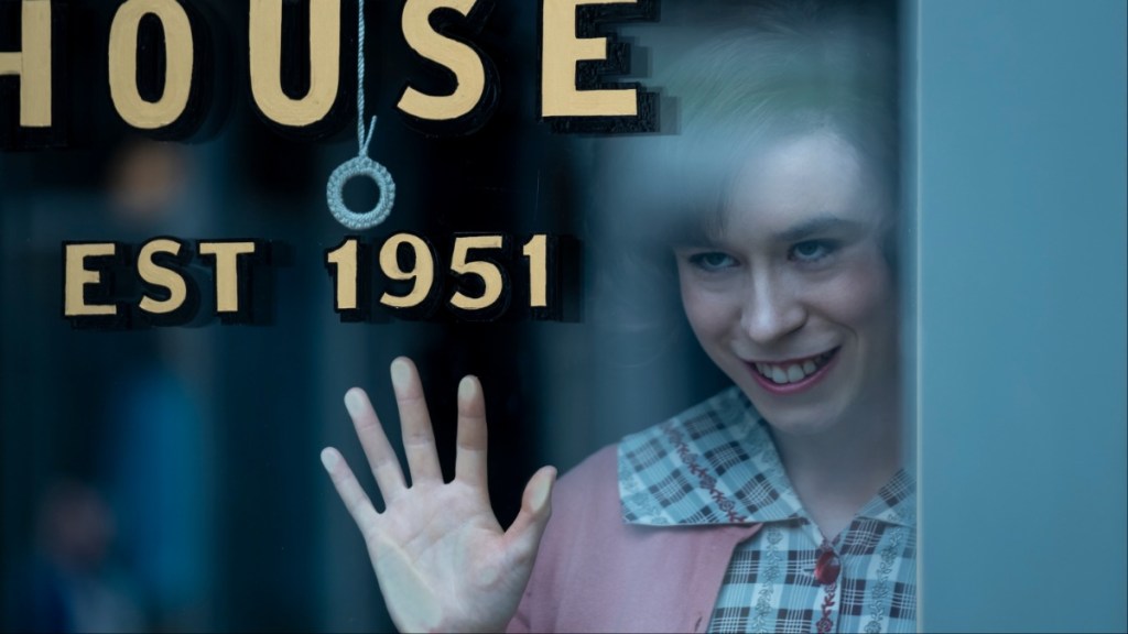 A woman puts her hand on glass and smiles.