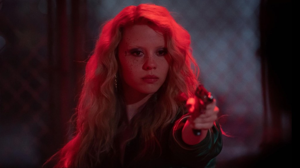 Mia Goth points a gun.