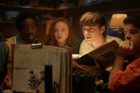 The cast of Stranger Things huddles around a table.