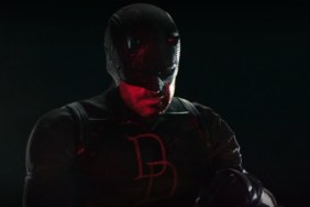 Matt Murdock in black costume observing police, lit by red light in Daredevil Season 2 Episode 2