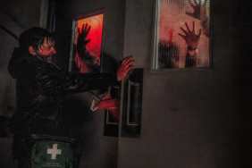 Austin Abrams stands in front of a door in Resident Evil.