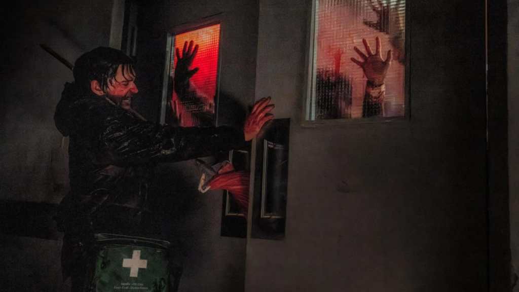 Austin Abrams stands in front of a door in Resident Evil.
